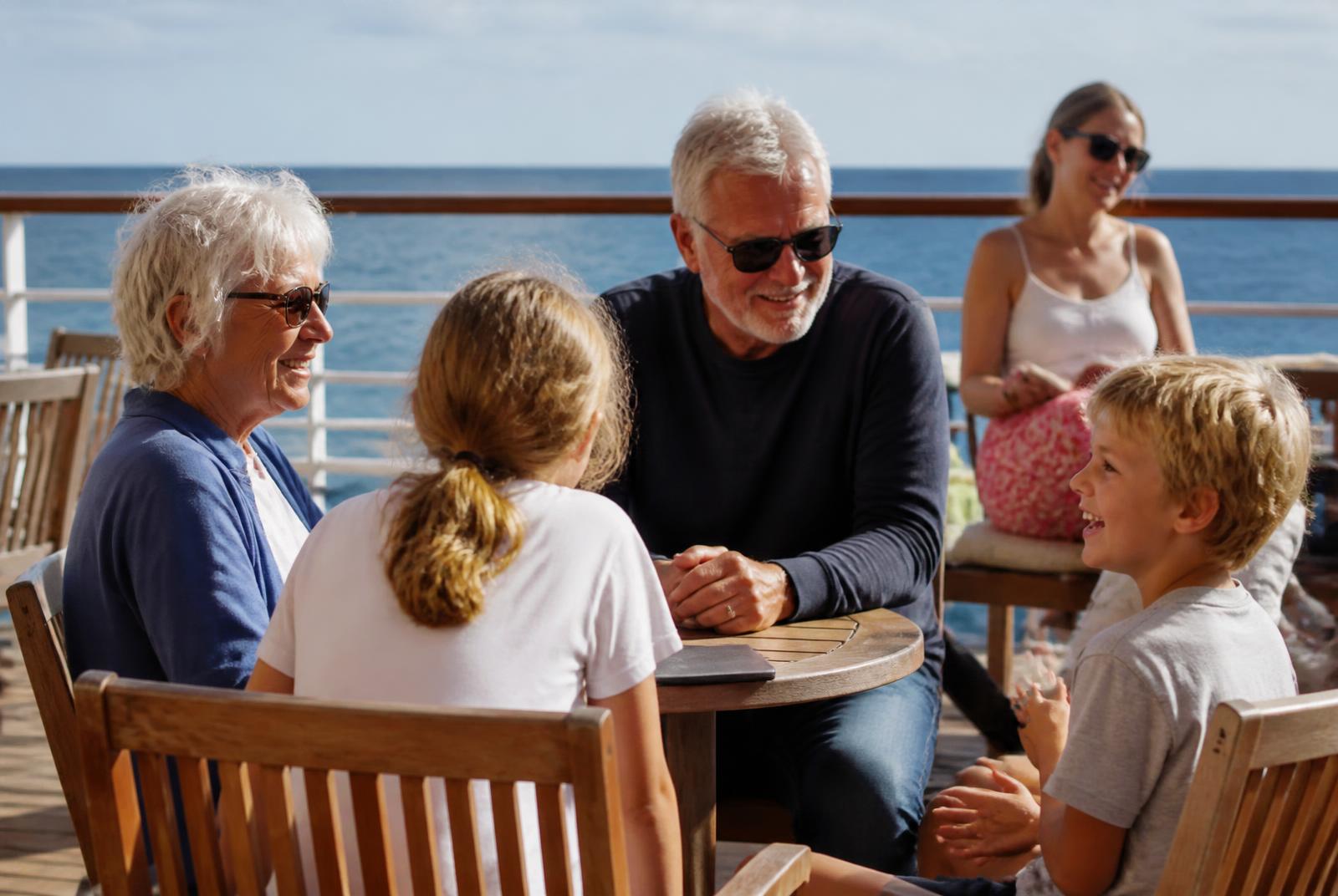 Família de diferentes gerações conversando em mesa no deck